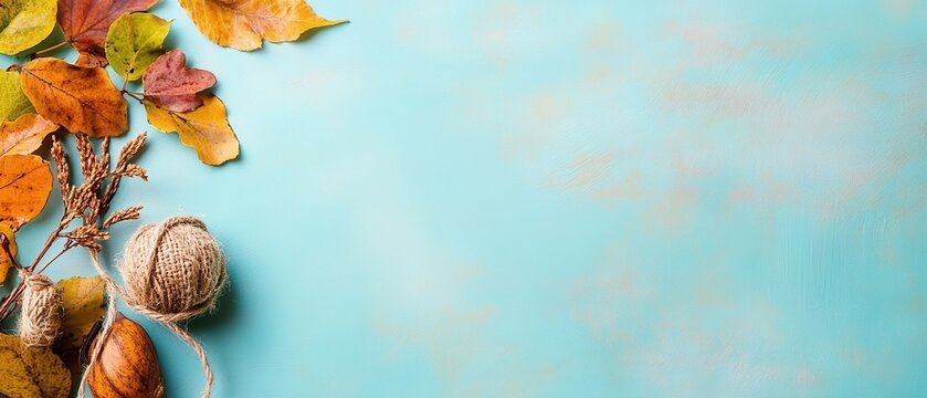 Autumn leaves, twine, and seed pods arranged on a light blue background create a rustic fall scene. Horizontal banner with copy space for text, poster, free space