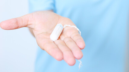 Woman gripping feminine hygiene product tampon, highlighting menstrual health awareness and personal care for women's wellness