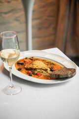 Portion of gourmet dorado fish with puttanesca sauce with wine
