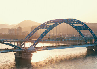 Aerial view of a bridge over a river with cars commuting at sunset. Hangzhou, China.