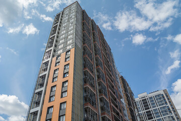 Obraz premium Construction work on the exterior cladding. Laying of thermal insulation material on the walls. Insulation of a high-rise building. Plastering the walls. Balconies of a house under construction.