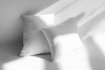 Two fluffy white pillows on white background under sunlit shadows for peaceful concept