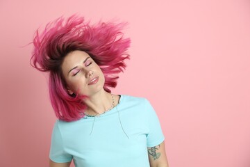 Beautiful woman with bright dyed hair shaking head on pink background, space for text