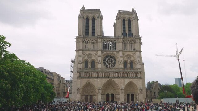 View on the medieval Catholic cathedral church Notre-Dame de Paris in French Gothic style and crowd of tourists at the Place Jean-Paul II on the island Ile de la Cite, 4th arrondissement of Paris.