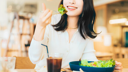 カフェでランチを食べる笑顔の女性・ビジネスウーマン