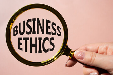 Business ethics symbol. Concept word Business ethics on magnifying glass. Businessman hand....