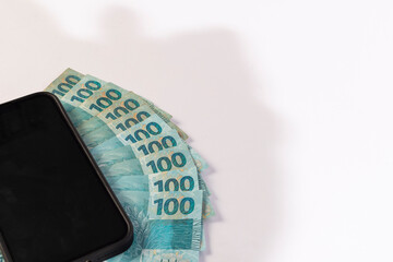 Black Cellphone and Brazilan 100 Reais Banknotes on a white background