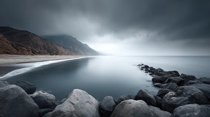 A coastal scene with an overcast sky filled with heavy, rolling clouds casting a cool, gray tone over calm ocean waters and rocky shorelines
