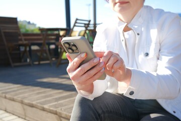 A person enjoying a sunny day outdoors, using a smartphone for digital activities and communication