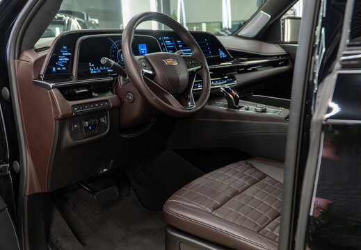 Cadillac Escalade luxury car interior, seats, steering wheel, shift lever, dashboard. The Cadillac Escalade SUV detail logo. Brown leather interior. American car.