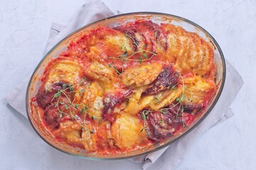 Sweet potato, parsnips and beet root au gratin with thyme and melted cheese, horizontal top view