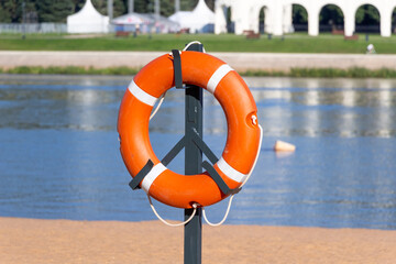 A lifebuoy secured to a holder on the shore on a summer day