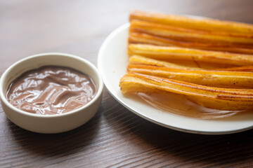 Churros sticks with chocolate sauce on a white plate