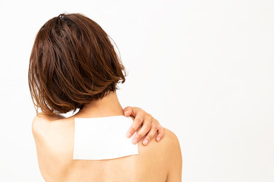 肩甲骨に湿布を貼った女性