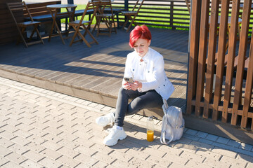 A woman enjoying her time using a smartphone while seated in a cozy outdoor cafe setting