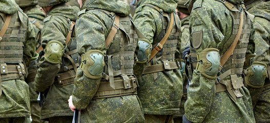Fototapeta premium Soldiers in tactical gear parade during a military event in a city square on a bright afternoon