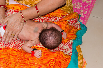 Indian woman’s hand, gently giving traditional oil massage to a newborn baby who is lying on her thighs. Indian traditions, baby care, mother-child bonding, early parenting, cultural wellness rituals.