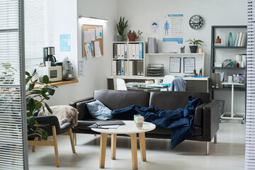 Light-filled office featuring a cozy sofa, coffee table, and well-organized shelves. Office tools and decor add to the modern yet comfortable setting