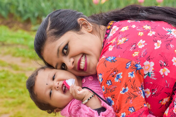 Young Indian Asian mother laughing joyfully while holding her smiling baby in her arms. motherhood, parenting, childcare, emotional connection, and family love concept