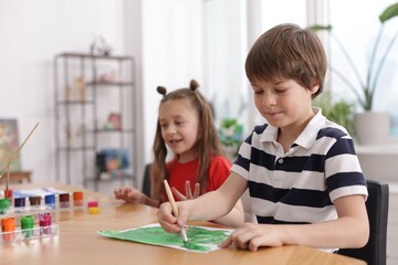 Kids painting at table indoors, selective focus. Learning to draw