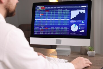 Stock exchange. Man analysing financial market on computer at desk indoors, closeup