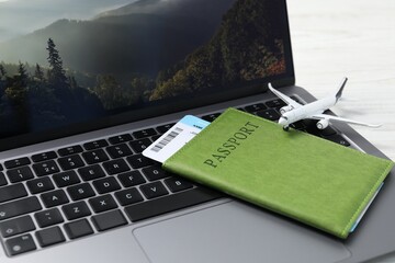 Passport, flight ticket, plane model and laptop on table, closeup
