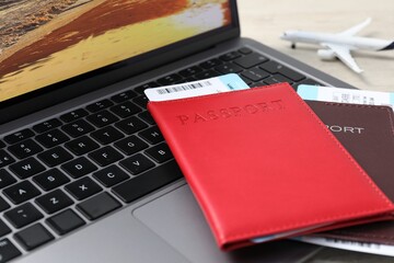 Passports, flight tickets, plane model and laptop on table, closeup