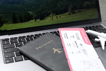 Passport, flight ticket, plane model and laptop on table, closeup