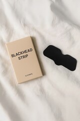 Blackhead removal strip and minimalist packaging on soft fabric surface — simple, effective skincare for clearer pores.