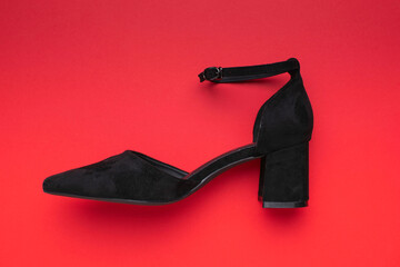 Chic Black Suede Heeled Shoe on Vibrant Red Background in Modern Fashion Display