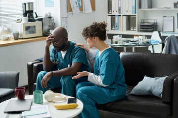Medical professionals wearing scrubs resting in staff room during break, showing emotions of...