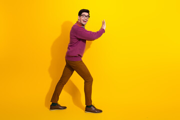 Smiling young man wearing trendy clothes gestures confidently against a vibrant yellow background for fashion