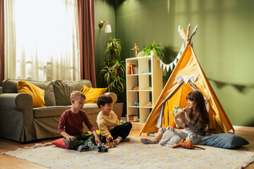 Children playing with toys in cozy living room with teepee tent © MexChriss