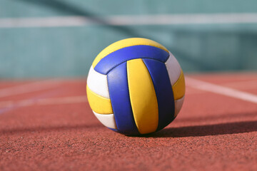 Close-up of yellow blue white volleyball on outdoor court in sunlight