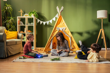 Children playing in cozy playroom with teepee tent, reading and enjoying toys