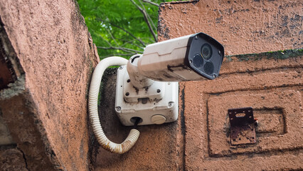 CCTV security camera on stone wall, modern outdoor surveillance camera securely mounted on a rugged...