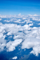 View of the blue sky with white clouds from an airplane window at high altitude