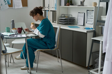 Healthcare worker in scrubs sitting at table in hospital break room having lunch break....