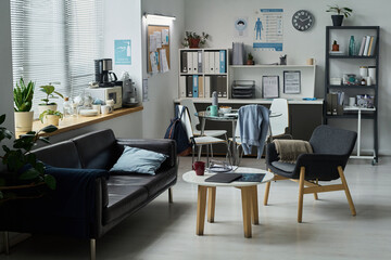 Cozy office space featuring neatly organized desks, shelves, and chairs. A coffee maker and coffee...