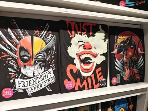 Palma De Mallorca, Spain - May 27, 2025: Colorful comic book art prints featuring Deadpool, a clown, and a bird, displayed on a shelf in a vibrant store, showcasing unique artistic styles