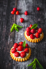 Homemade strawberry tartlets on dark wooden table