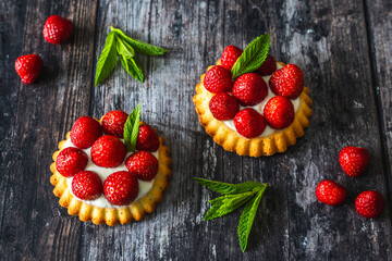 Homemade strawberry tartlets on dark wooden table