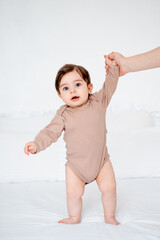 the baby learns to walk by taking the first steps, the mother holds the hand of a small child teaching him to walk