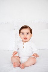 a baby on a white bed at home, a place for text, a cute smiling little child getting ready for bed, a portrait of a little boy child