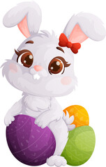 Cute Easter Bunny Girl with a Bow Sitting on Colorful Decorated Easter Eggs.