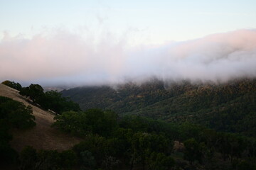 Blanket of fog rolling over a mountain ridge at sunrise