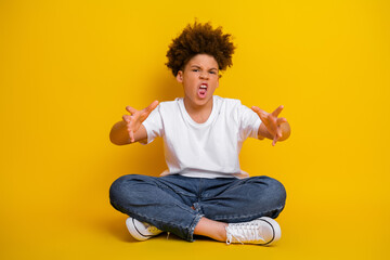 Energetic young boy making playful gestures against a vibrant yellow background, expressing humor, confidence, and creativity