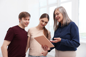 Smiling real estate agent with tablet working with couple at home