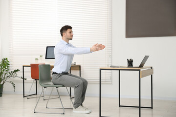Handsome man stretching on chair in office