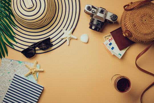 Top view travel concept with retro camera films, map and passport on light orange background with copy space. Flat lay tourist essentials